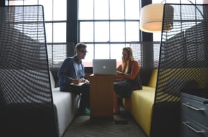 A man and a woman looking at a laptop during a video marketing consulting session.
